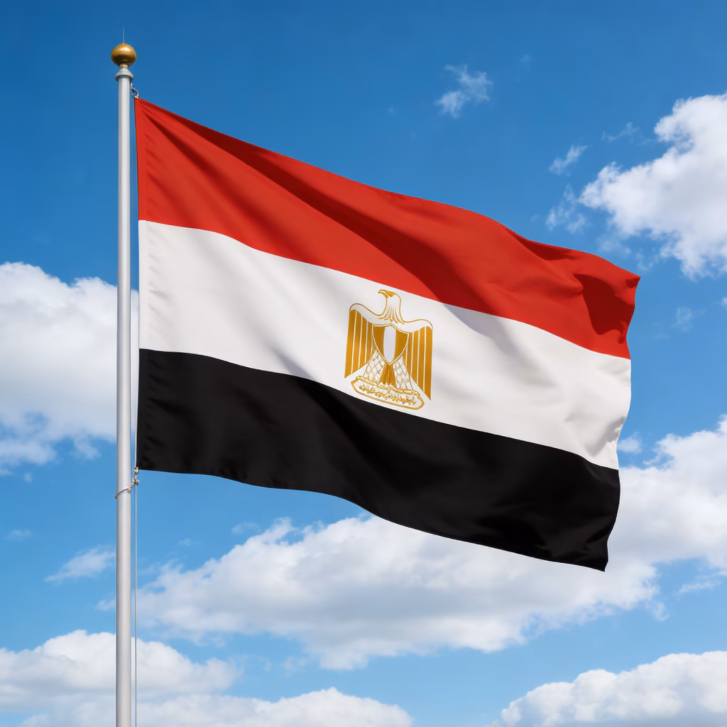 Egyptian flag waving on a silver flagpole, red white and black horizontal stripes with the golden eagle emblem, against a blue sky with clouds.